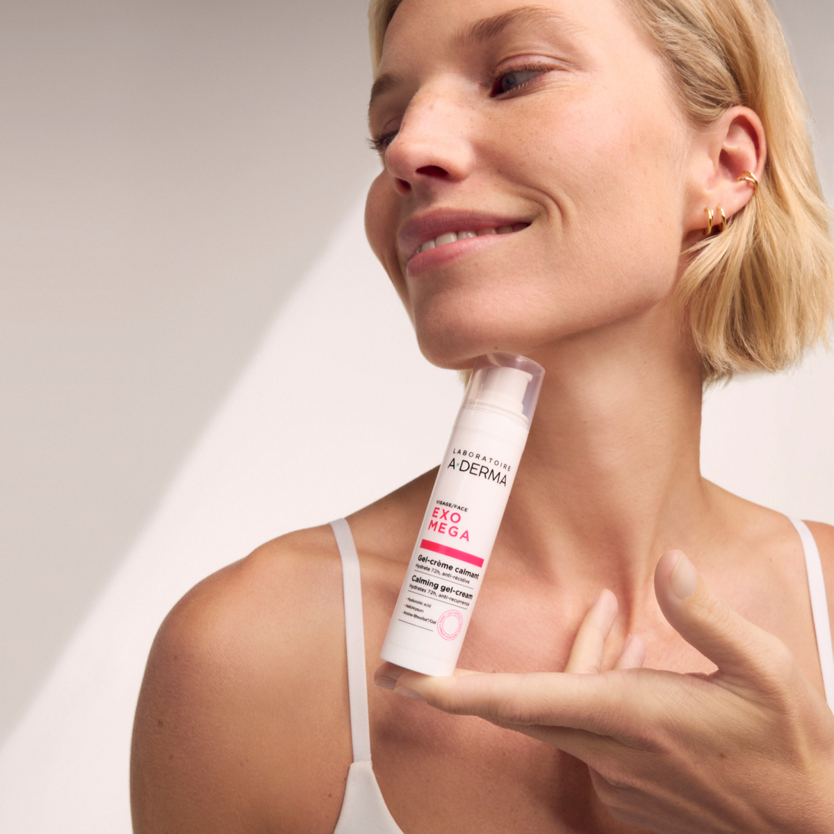 A-Derma Exomega, pump bottle held by a smiling woman