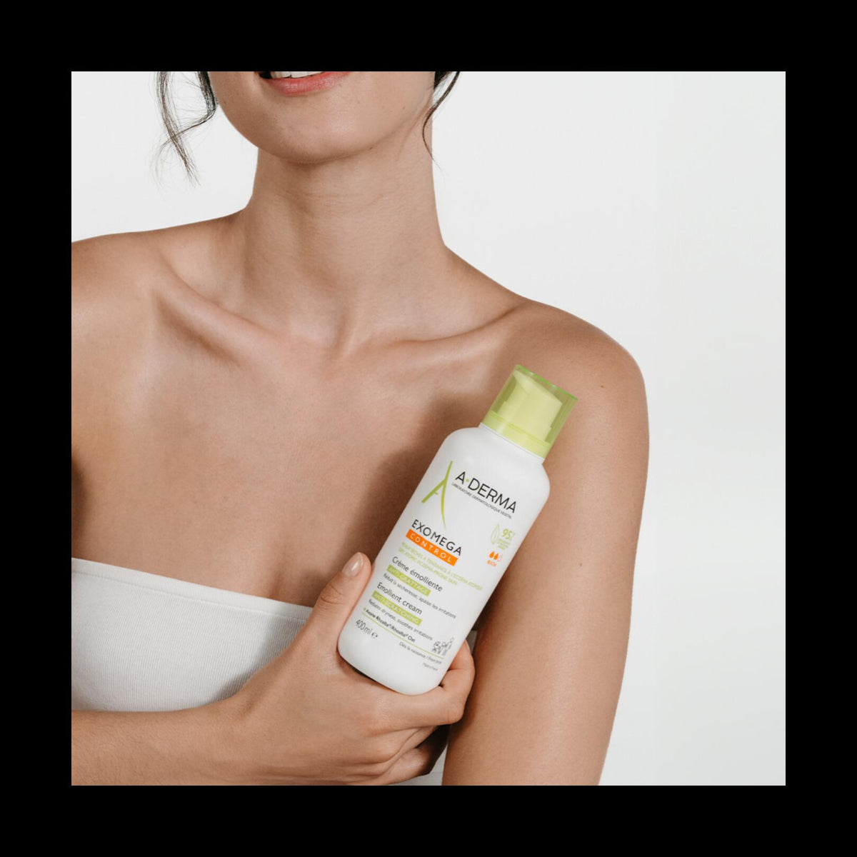 A-Derma Exomega Control, woman holding the pump bottle at her shoulder, black frame