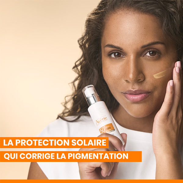 Avène Anti-Pigmentation, woman holding the pump bottle with a tinted swatch on her cheek