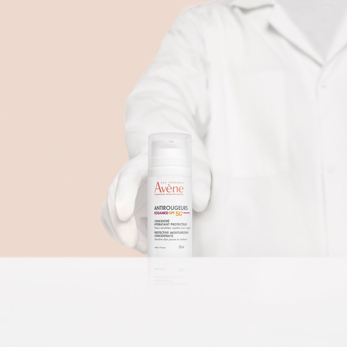 Avène Antirougeurs Rosamed, gloved hand of a person in a white coat holding the pump bottle