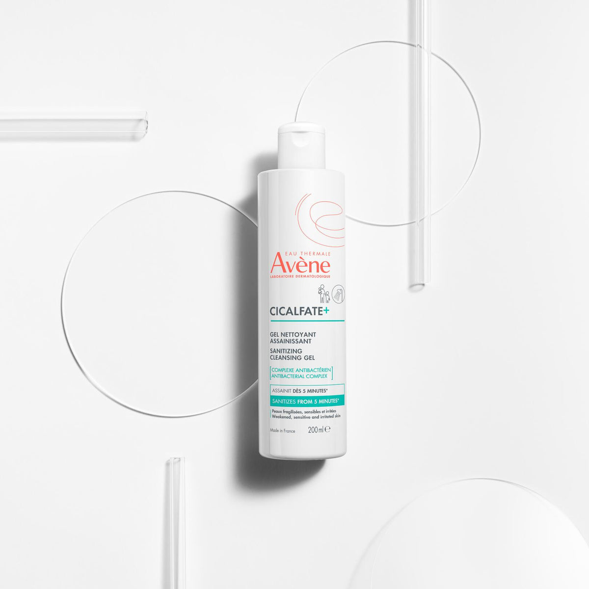 Avène Cicalfate+, bottle lying among glass discs and rods, top view