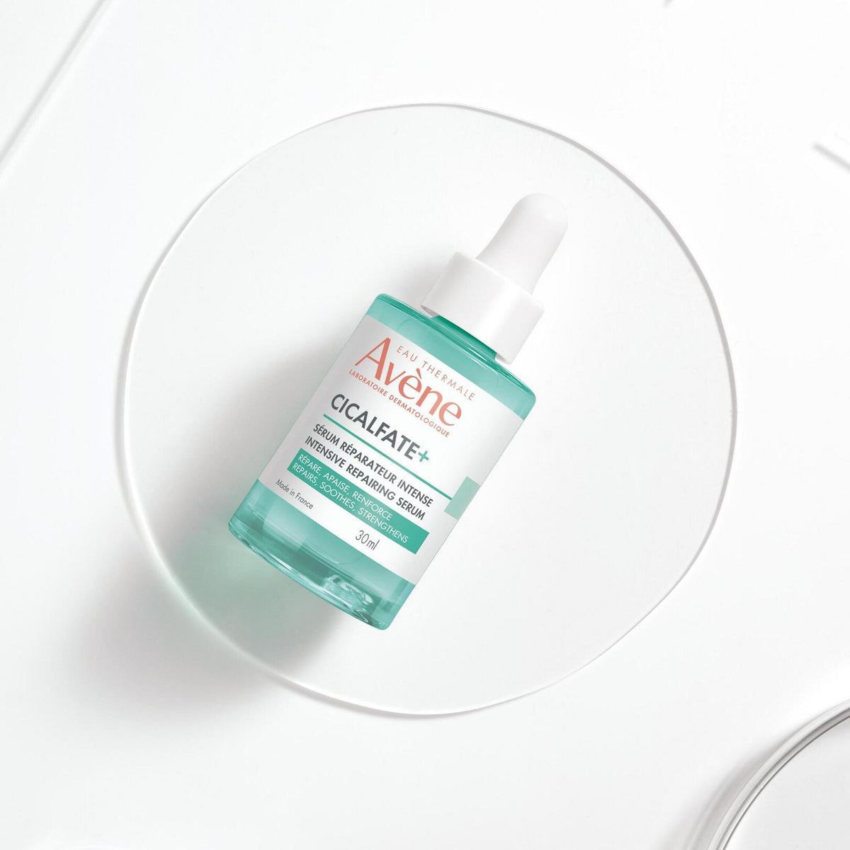 Avène Cicalfate+, dropper bottle lying on a glass disc, top view