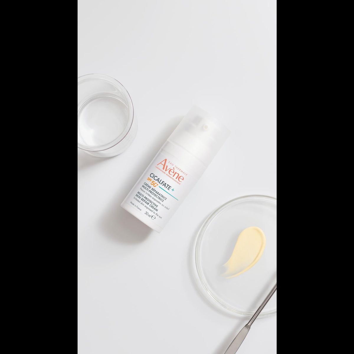 Avène Cicalfate+, pump bottle beside a glass dish with a cream sample and a spatula