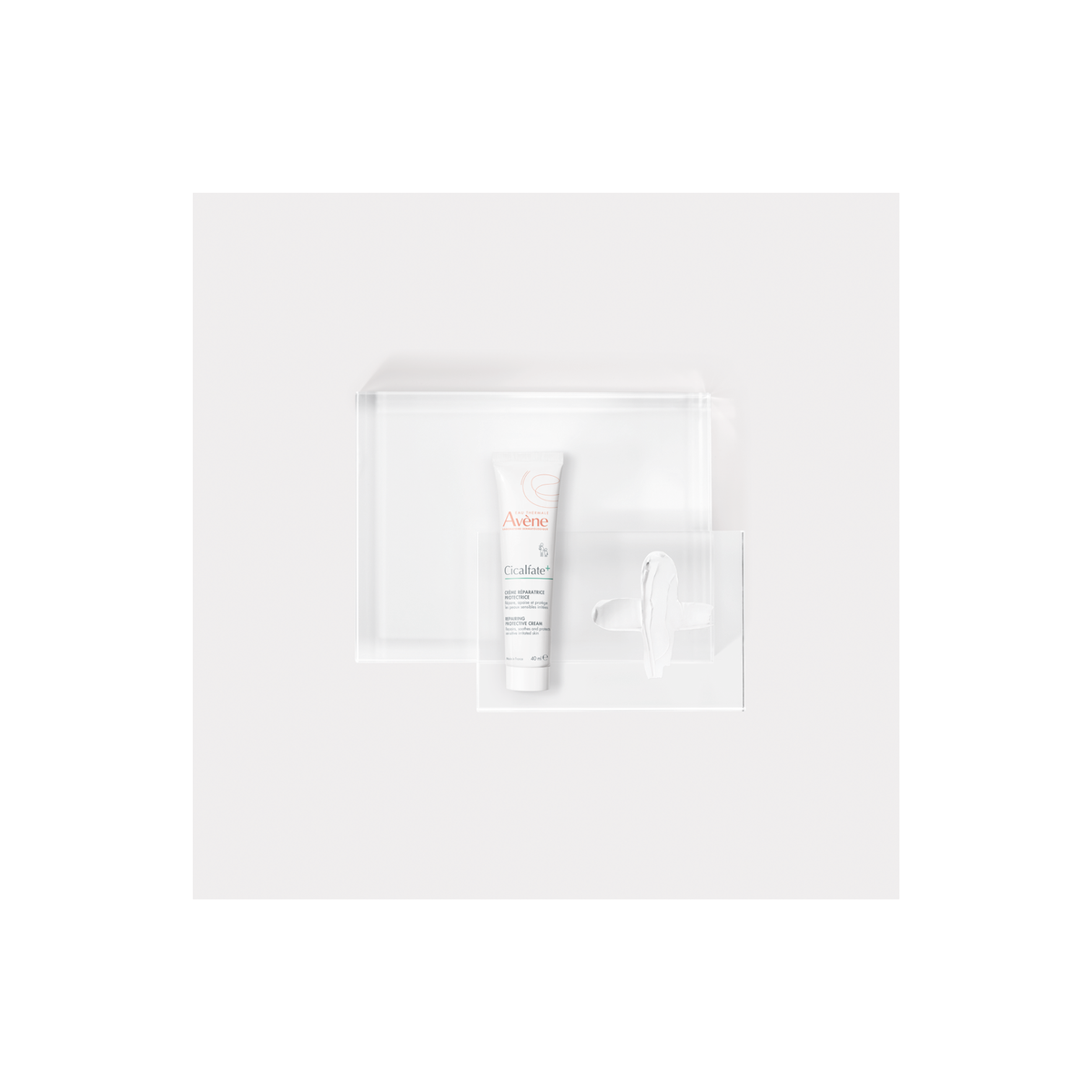 Avène Cicalfate+, tube on a glass block with a cream smear, top view