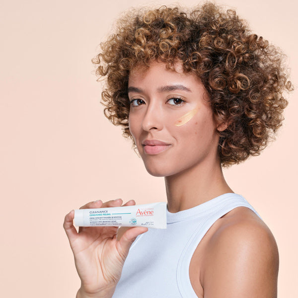 Avène Cleanance, woman holding the tube with a dab of cream on her cheek