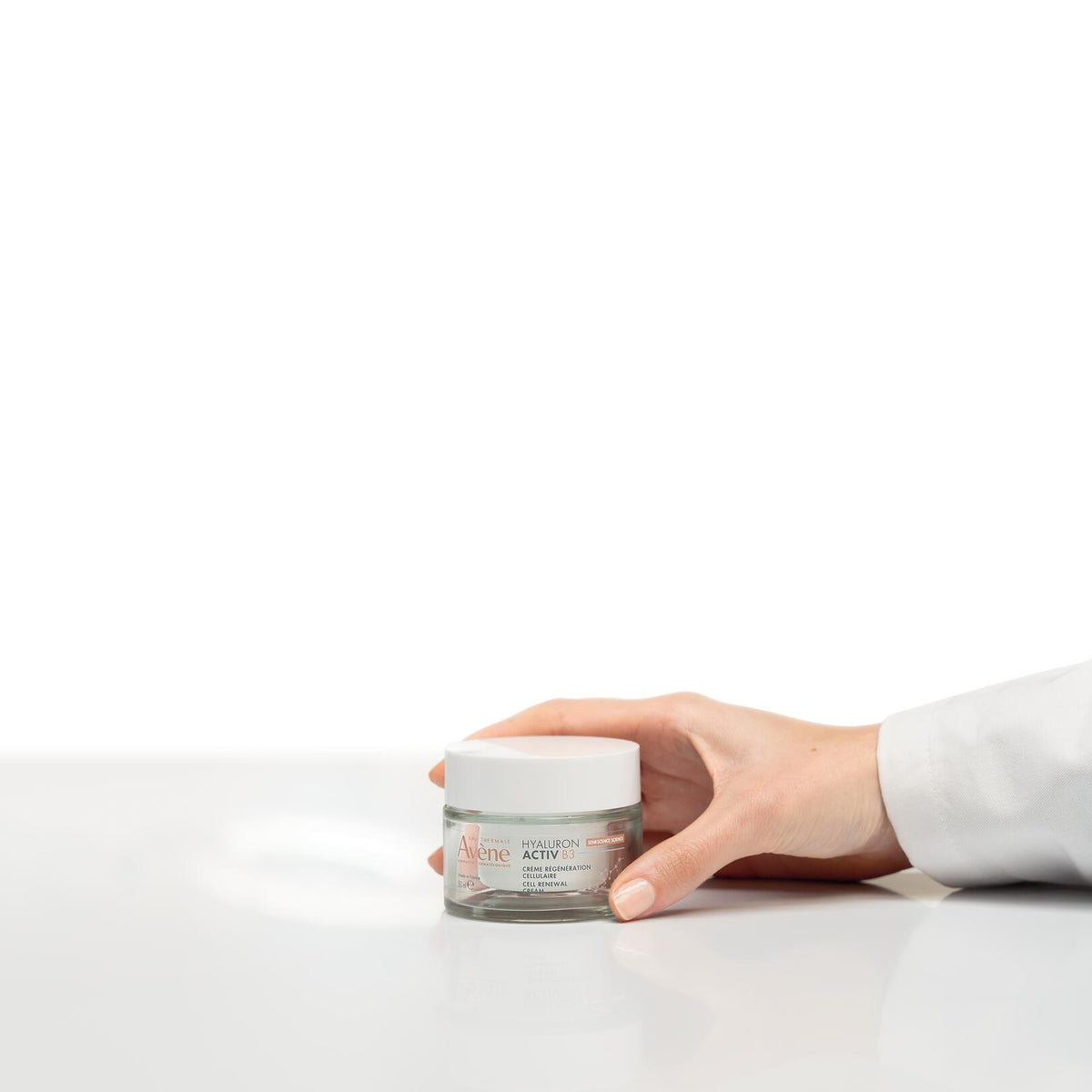 Avène Hyaluron Activ B3, hand setting the jar on a white surface