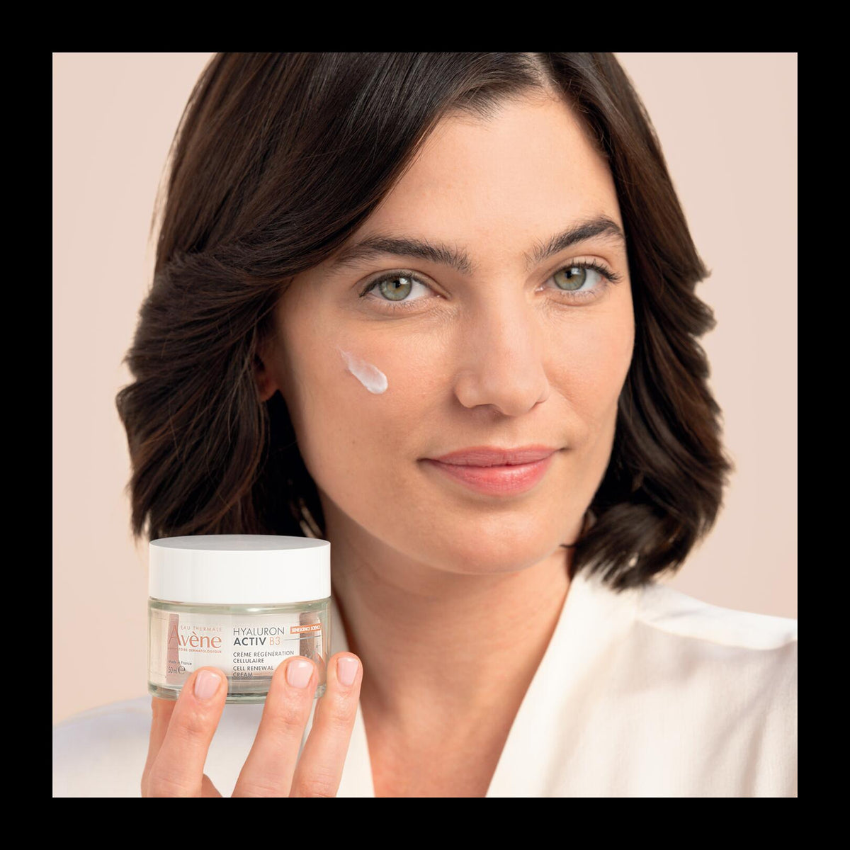 Avène Hyaluron Activ B3, woman holding the jar with a dab of cream on her cheek