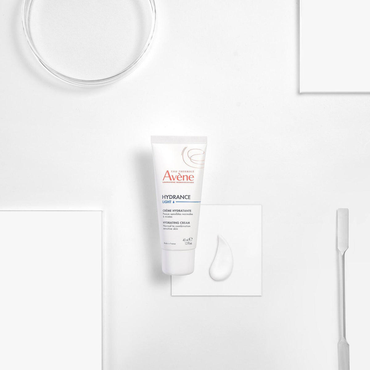 Avène Hydrance, tube with a cream swatch and a spatula on white blocks