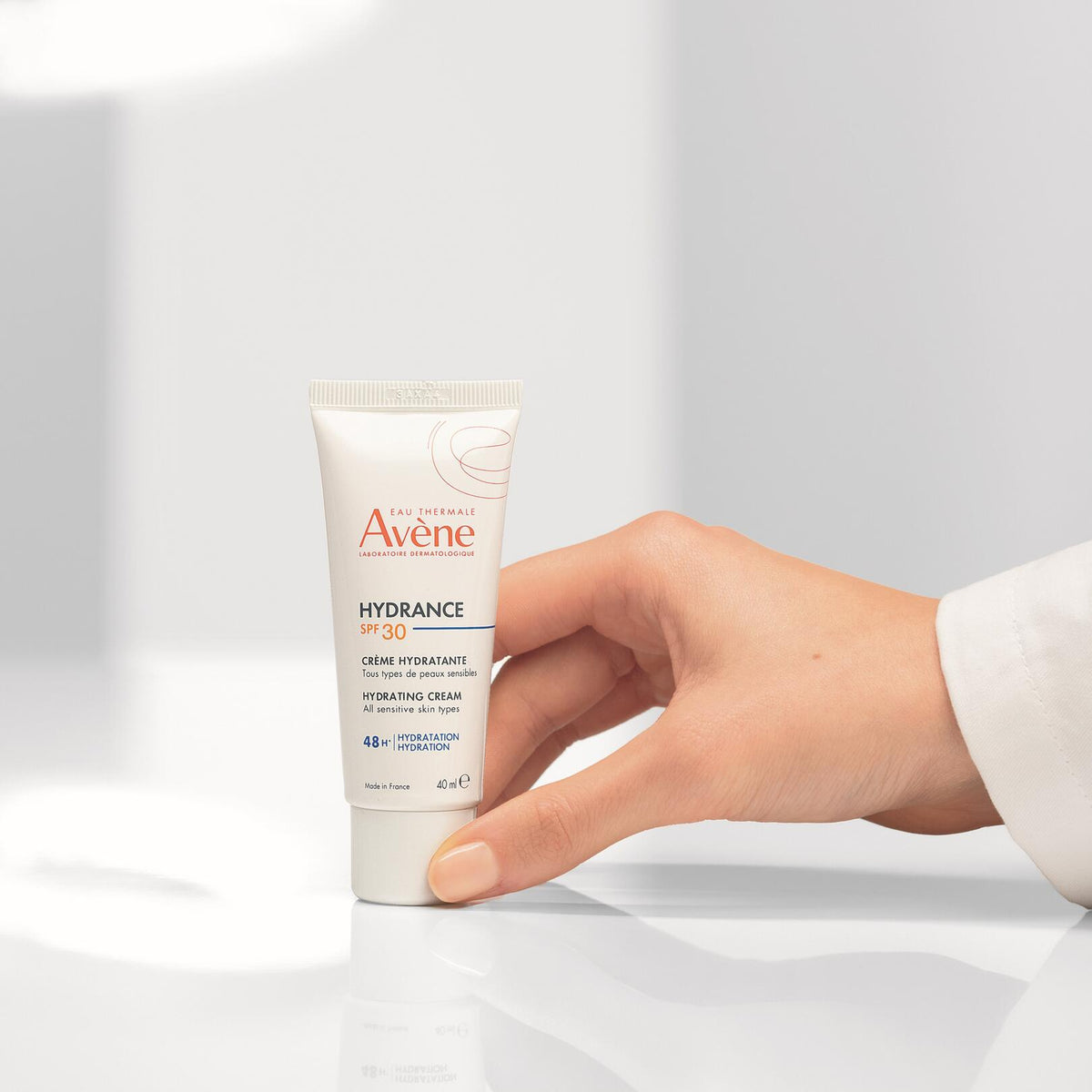 Avène Hydrance, hand placing the tube on a white surface