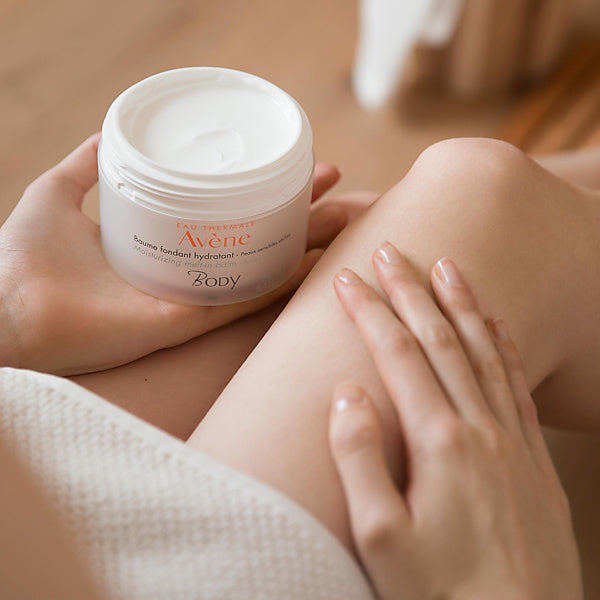 Avène Body, woman holding the open jar with a hand on her leg