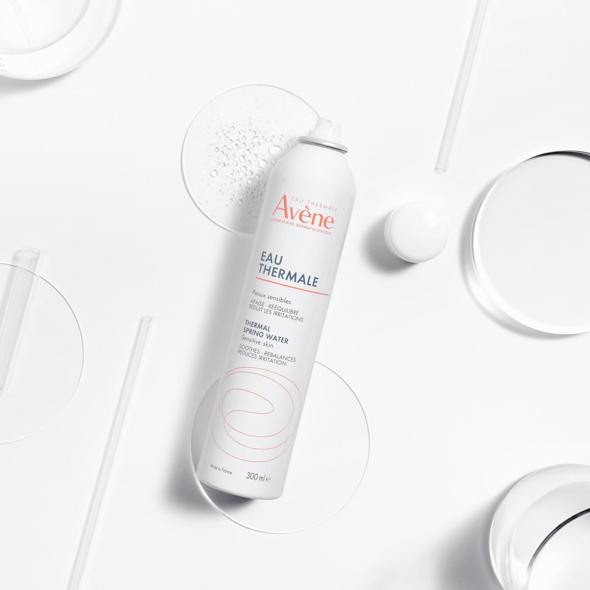 Avène Thermal Spring Water, spray can among glass dishes and droplets, close-up