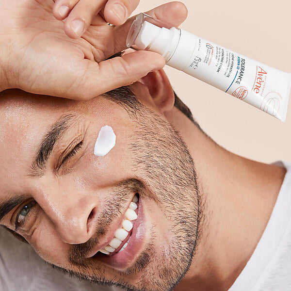 Avène Tolérance Hydra-10, smiling man with cream on his cheek holding the tube
