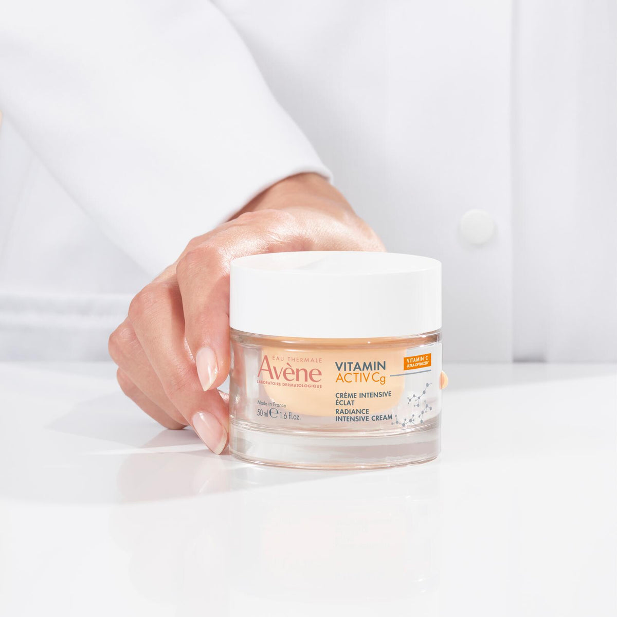 Avène Vitamin Activ Cg, hand in a lab coat holding the jar