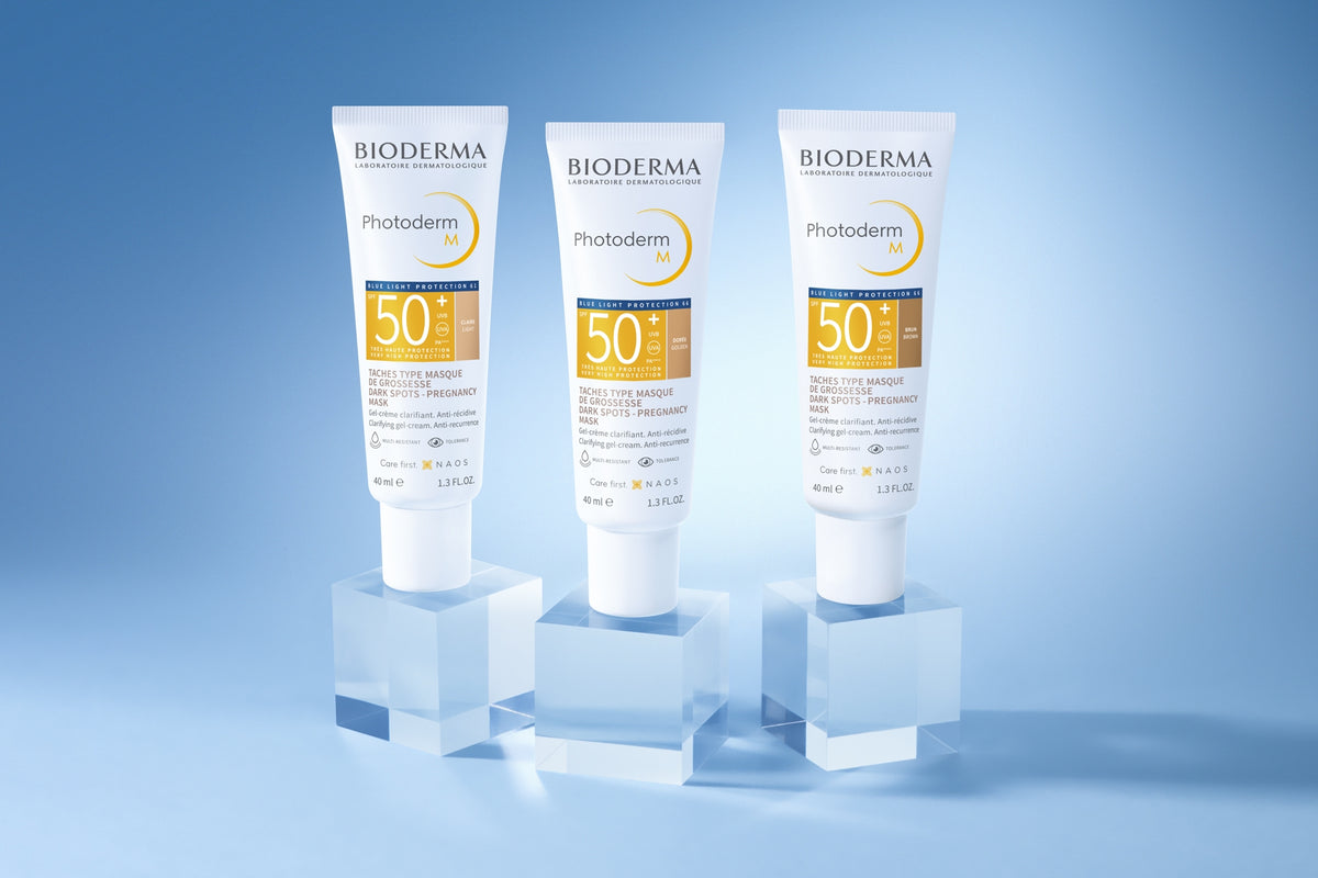 Bioderma Photoderm M, light, golden and brown tubes on clear cubes on a blue background