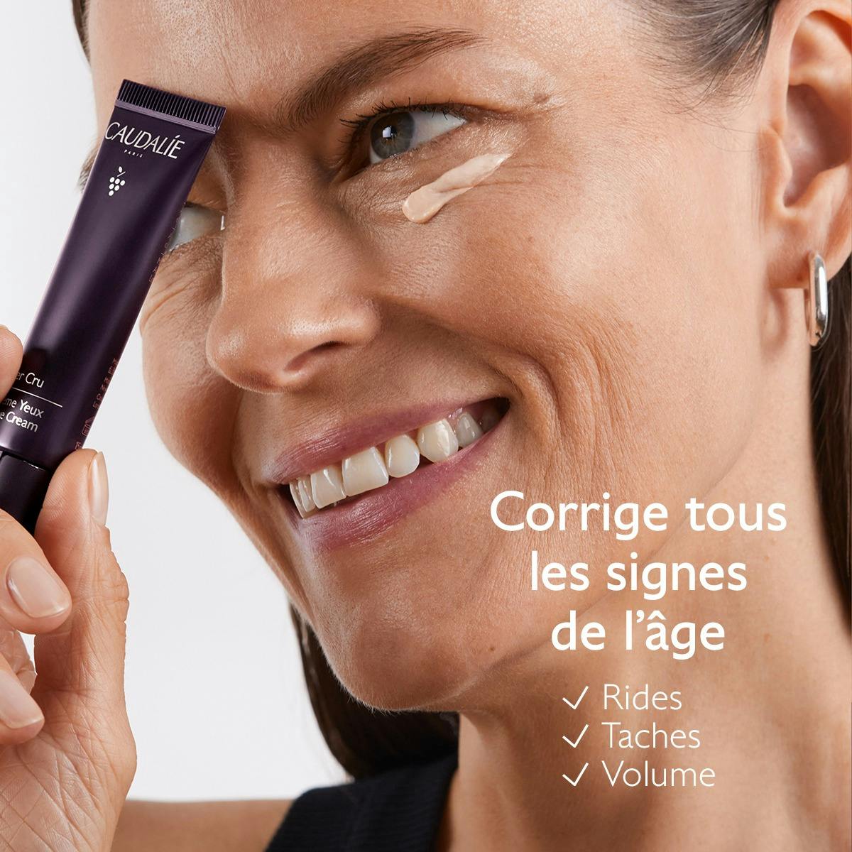 Caudalie Premier Cru, smiling woman holding the tube with cream under her eye