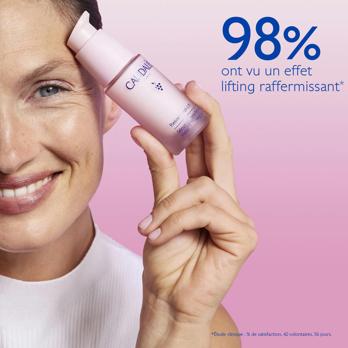 Caudalie Resveratrol-Lift, smiling woman holding the pump bottle by her temple