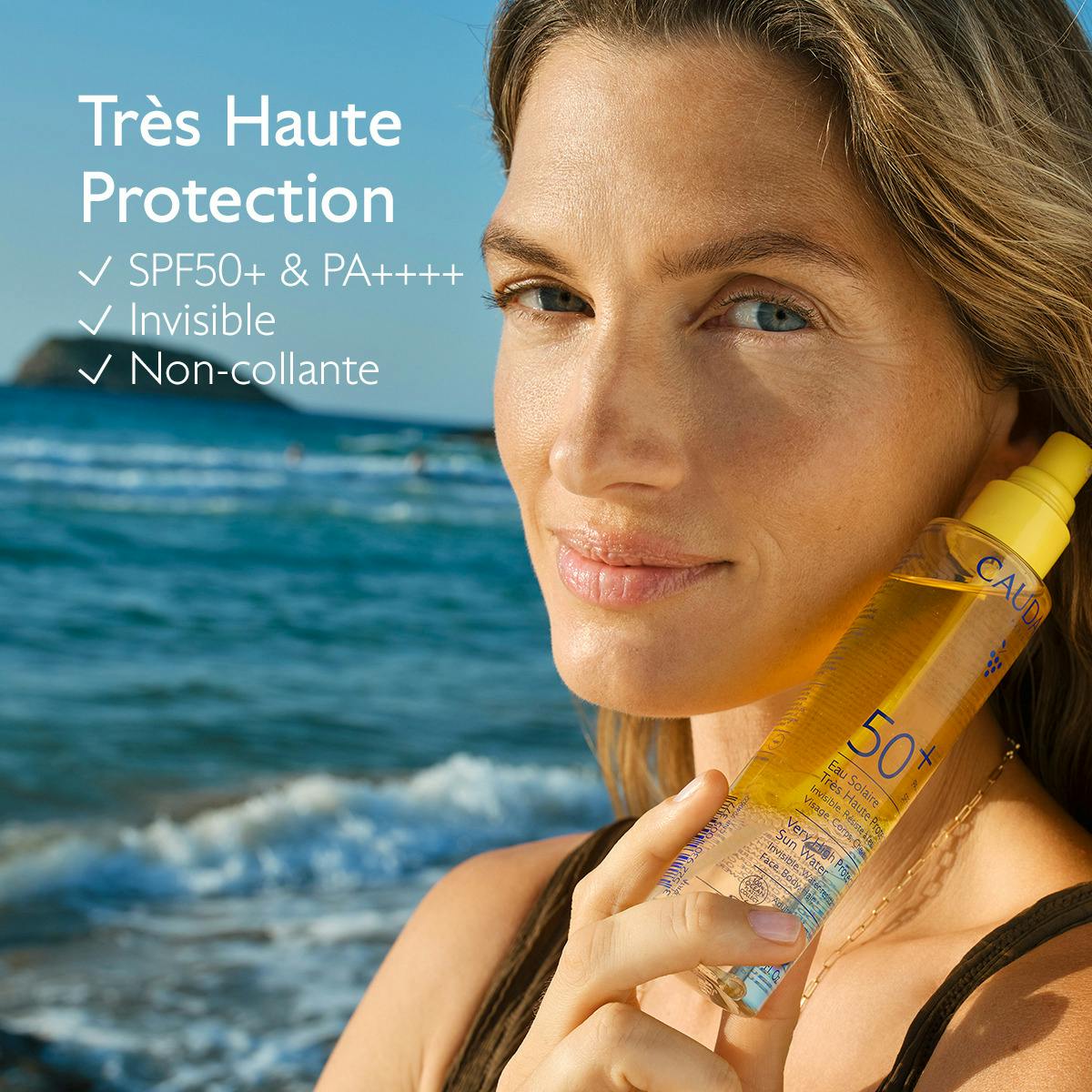 Caudalie Solaire, woman holding the Very High Protection Sun Water by the sea