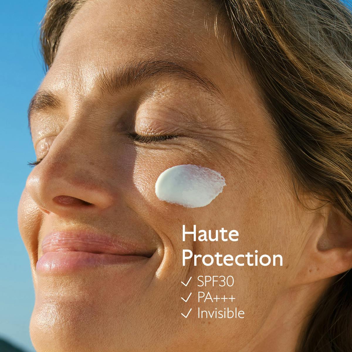Caudalie Milky Sunscreen Spray, woman with eyes closed and sunscreen on her cheek