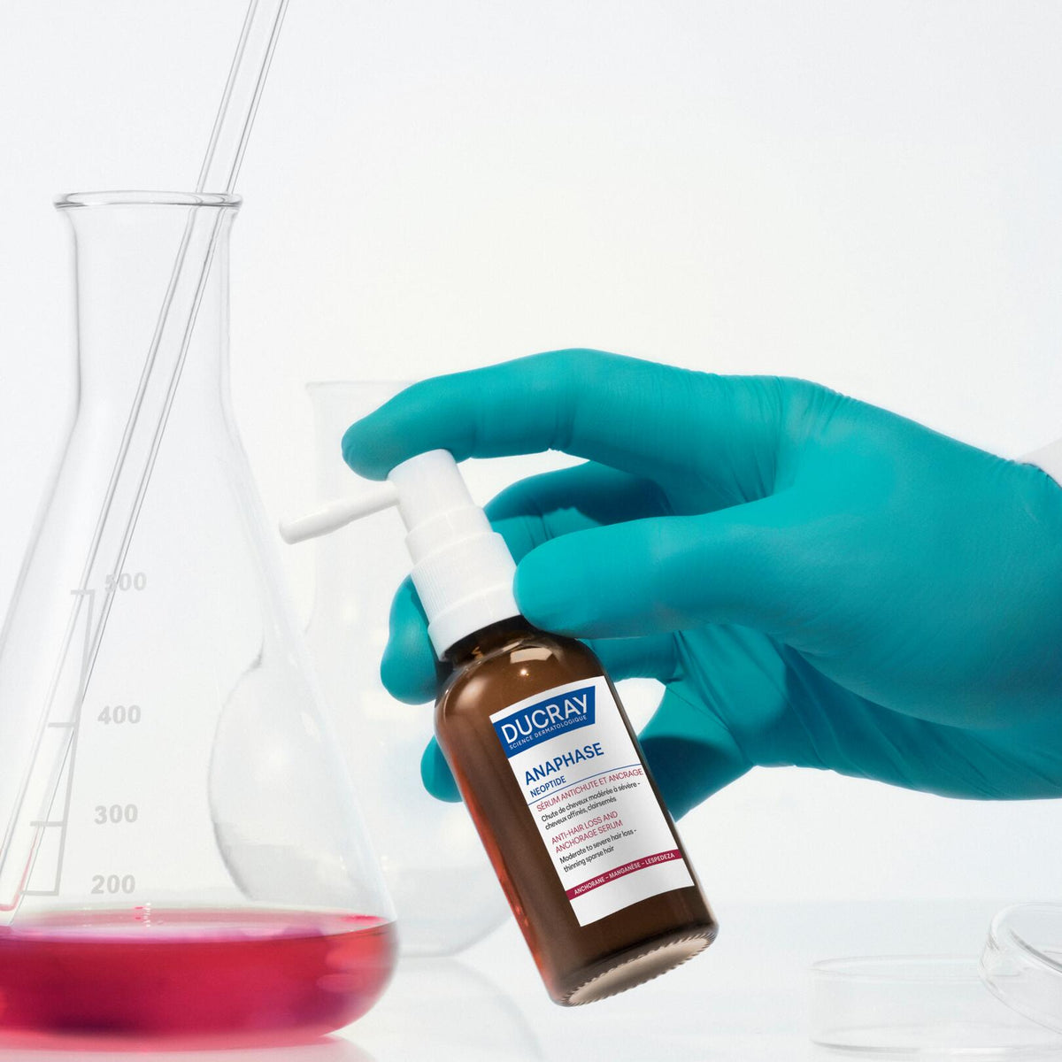 Ducray Neoptide, gloved hand holding the spray bottle in a lab
