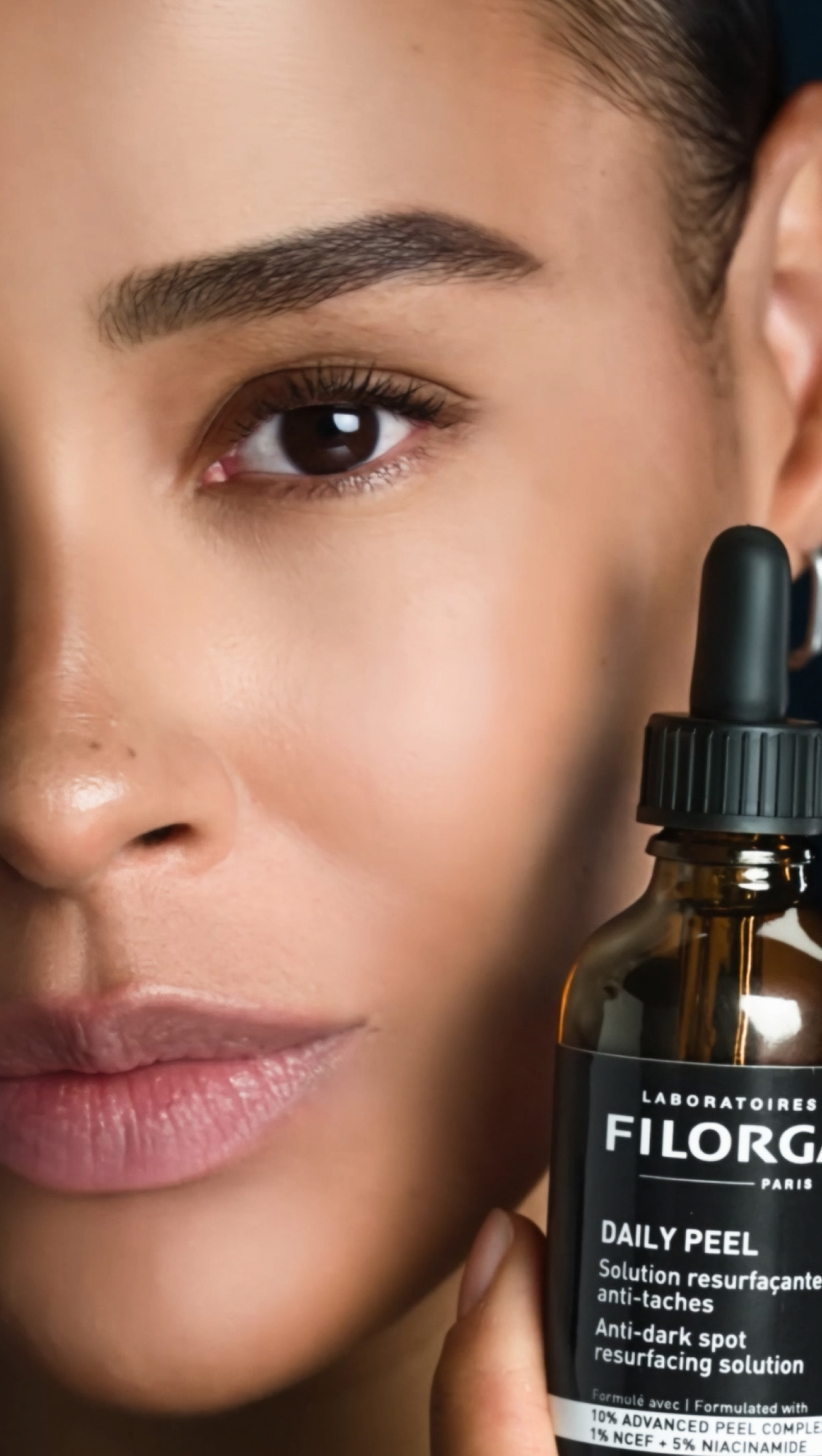 Filorga Daily Peel, model holding the dropper bottle