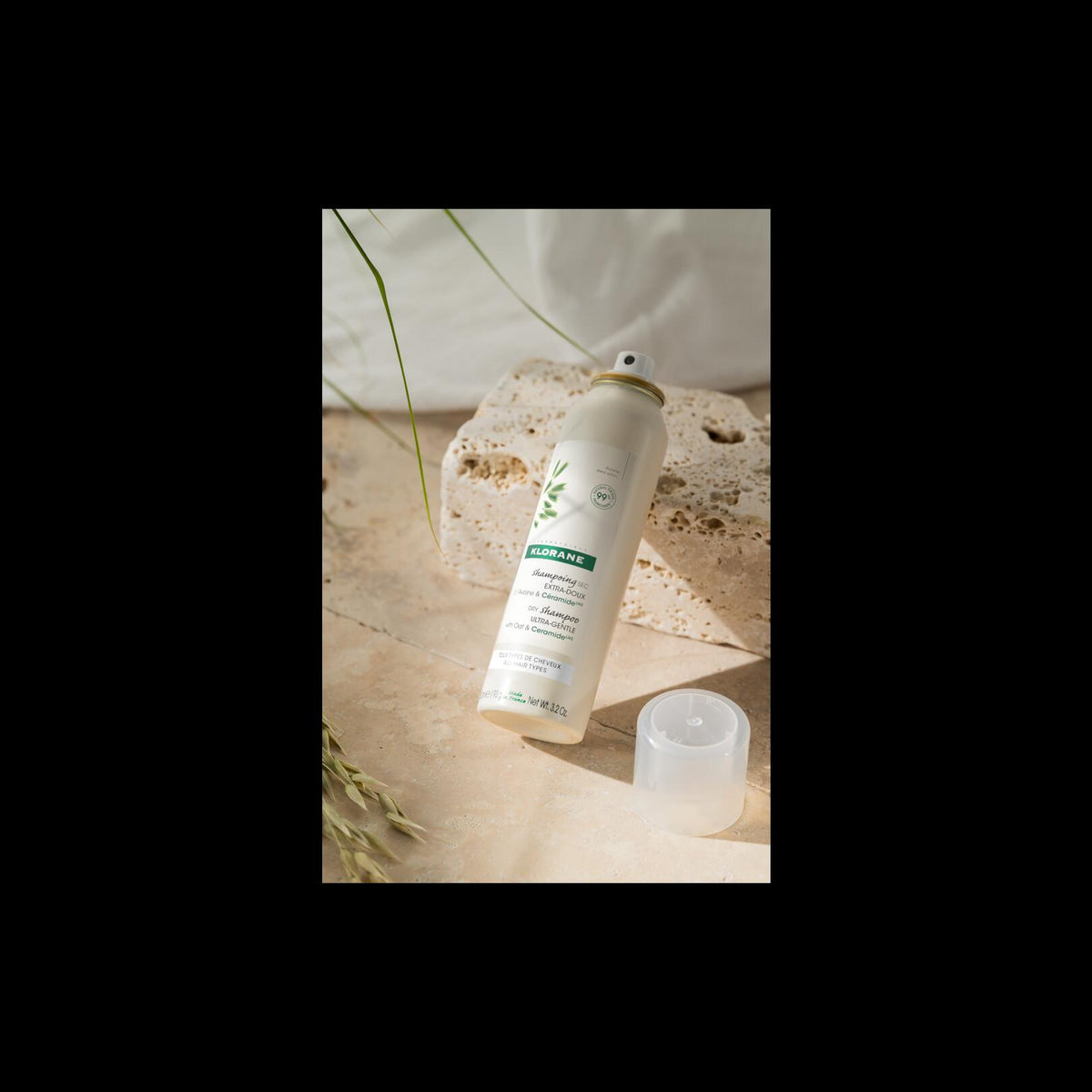 Klorane Oat Milk Dry Shampoo, spray can with the cap off on a travertine block