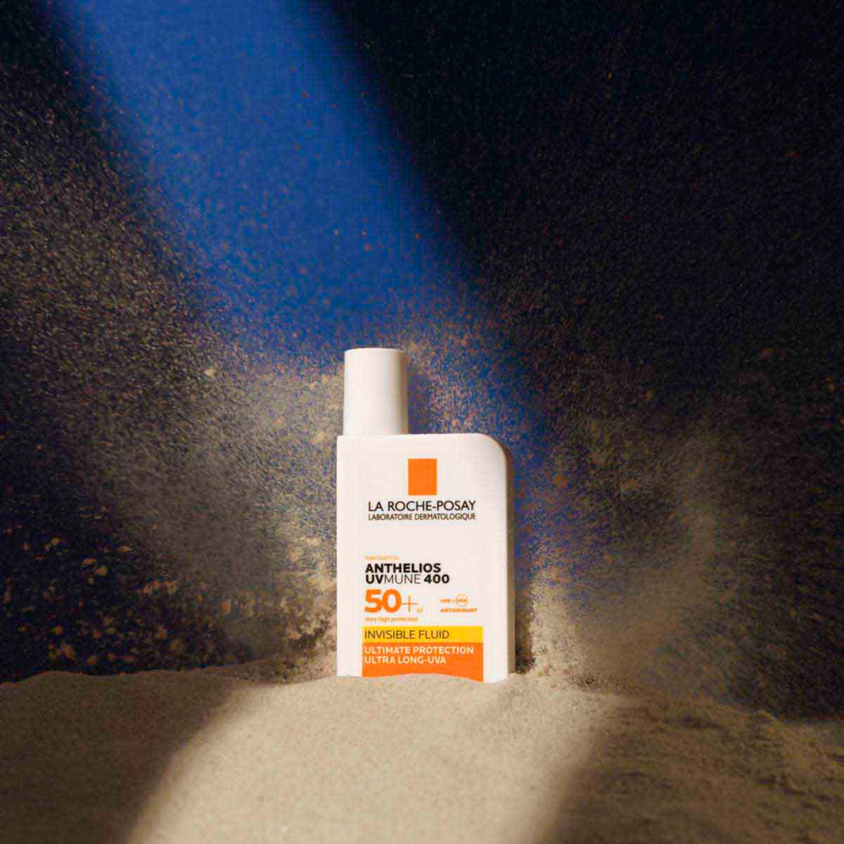 La Roche-Posay Anthelios UVMune 400 Invisible Fluid SPF 50+ bottle standing in sunlit sand