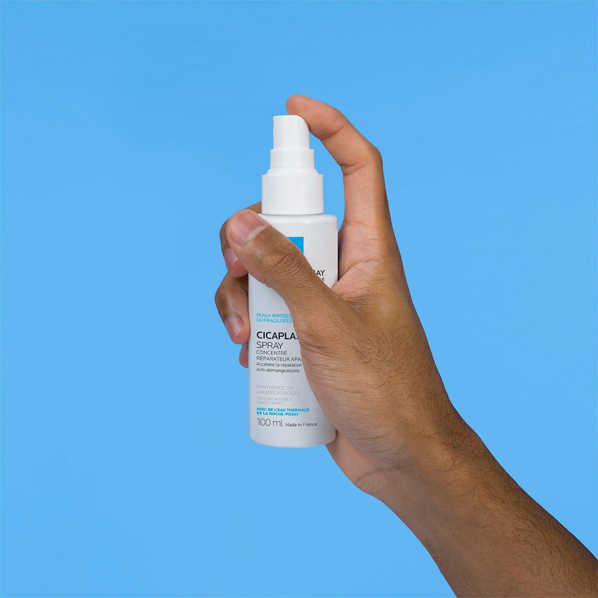 La Roche-Posay Cicaplast, hand holding the spray bottle on a blue background