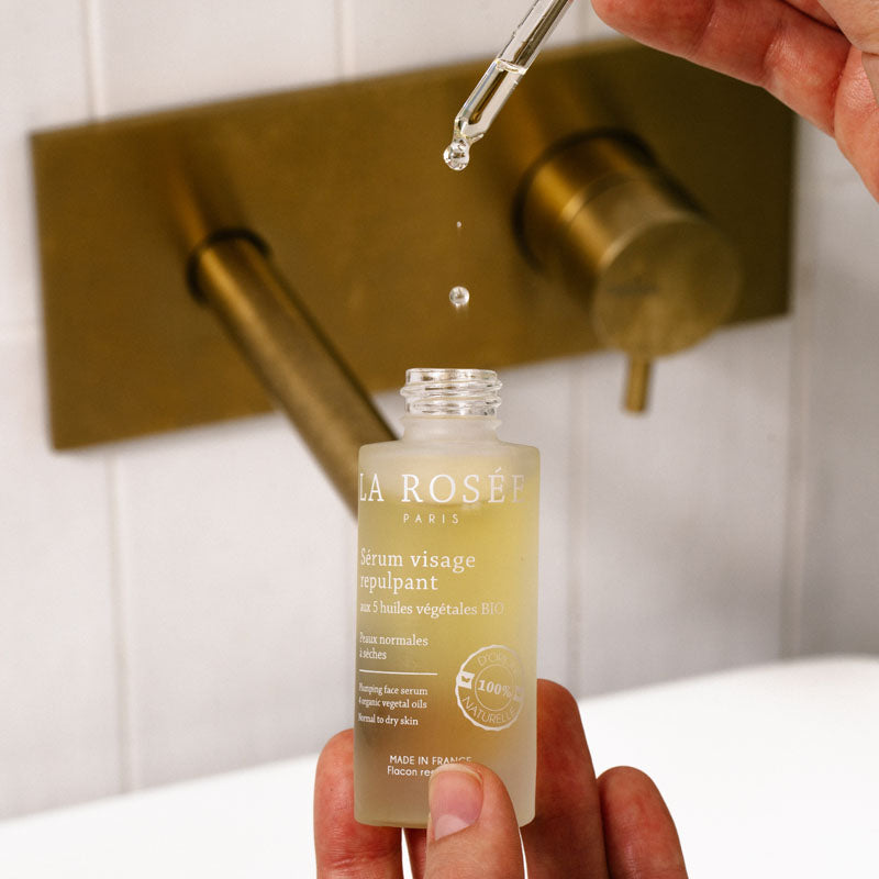La Rosée Plumping Serum, hand holding the open bottle under the dripping dropper