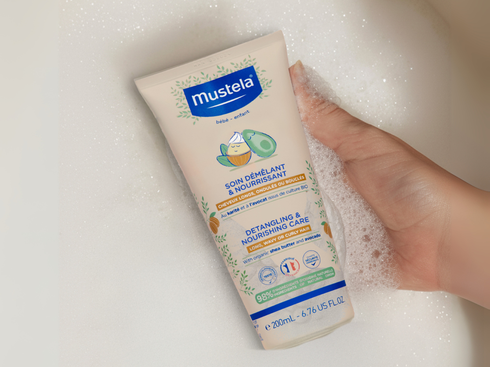 Mustela Detangling & Nourishing Care, hand holding the tube in bath foam
