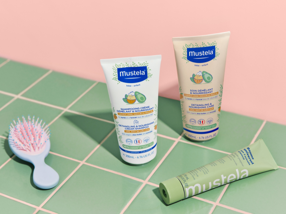 Mustela Detangling & Nourishing Care, three tubes and a baby hairbrush on green tiles