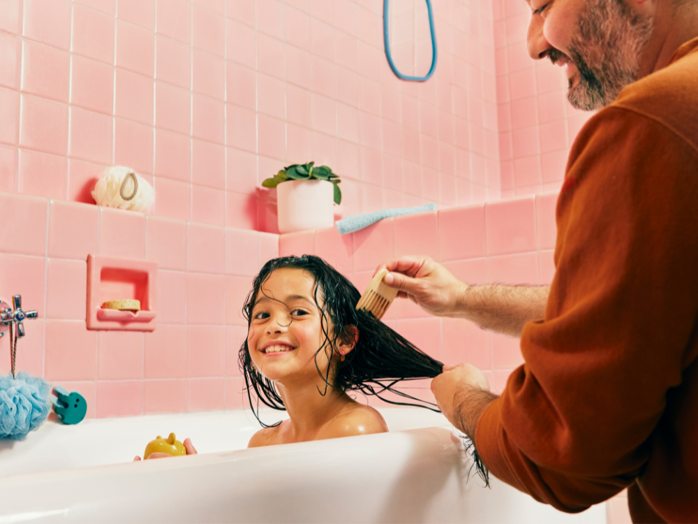 Mustela Detangling Cream Shampoo, bearded man combing a smiling girl's wet hair in the bath