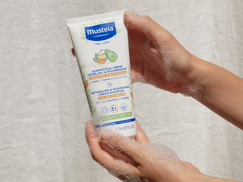 Mustela Detangling Cream Shampoo, foamy hands holding the tube