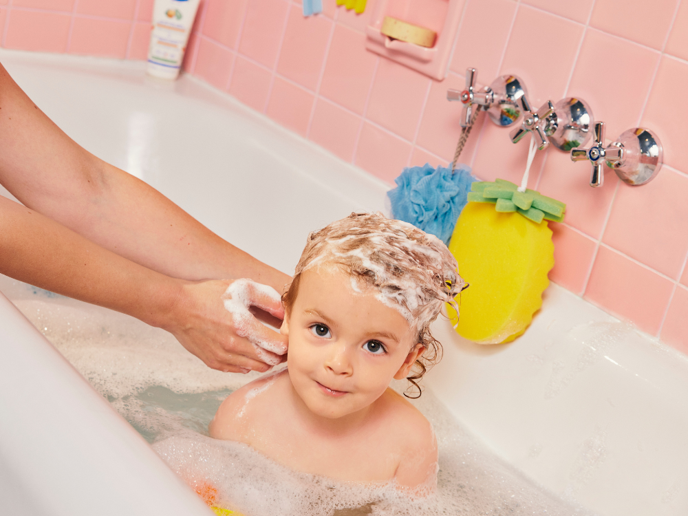 Mustela Detangling Cream Shampoo, adult shampooing a toddler's hair in the bath