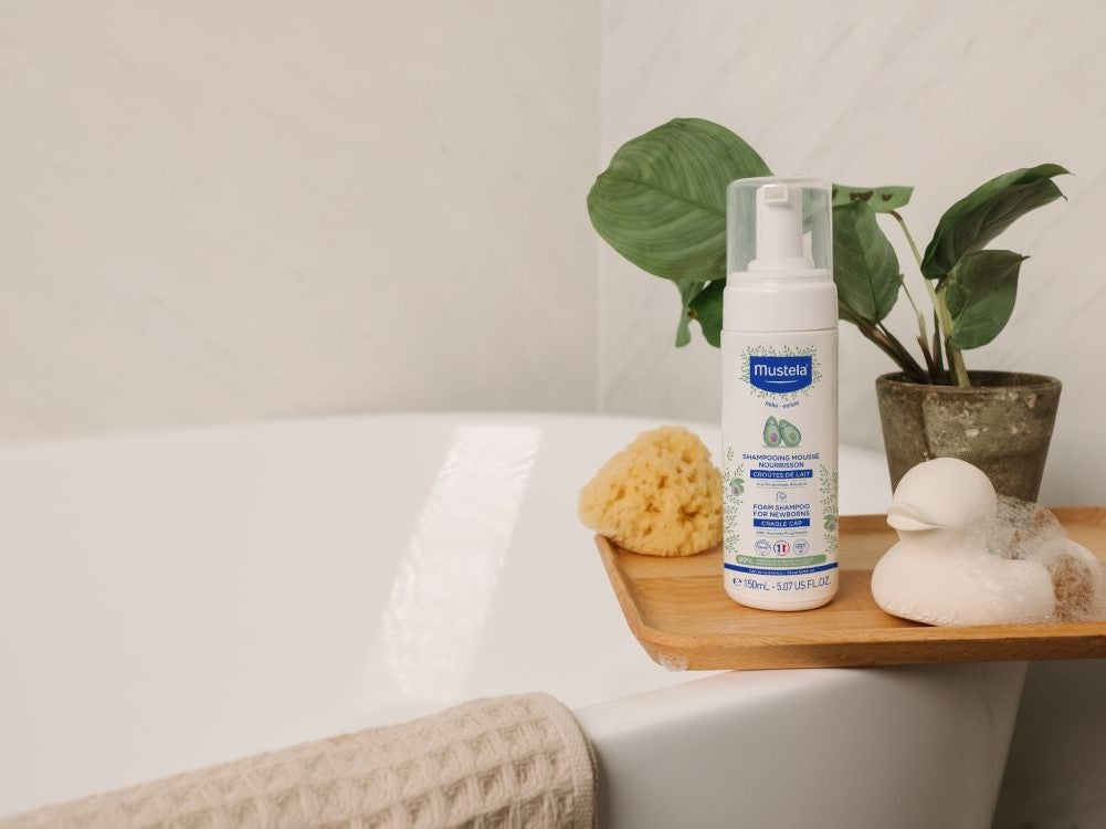 Mustela Baby Foam Shampoo, pump bottle on a bath tray with a sponge and a rubber duck