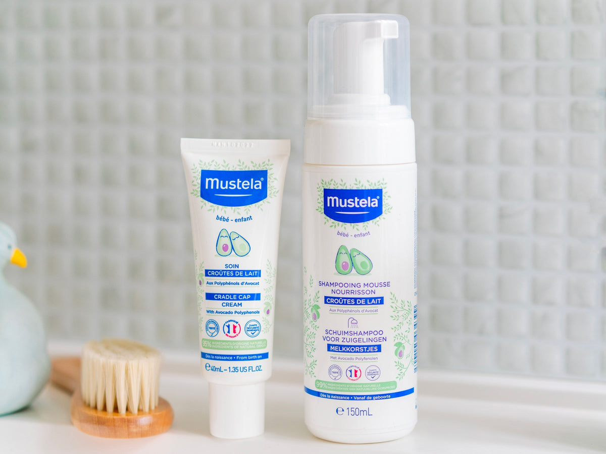 Mustela Baby Foam Shampoo, pump bottle beside a cream tube and a baby brush