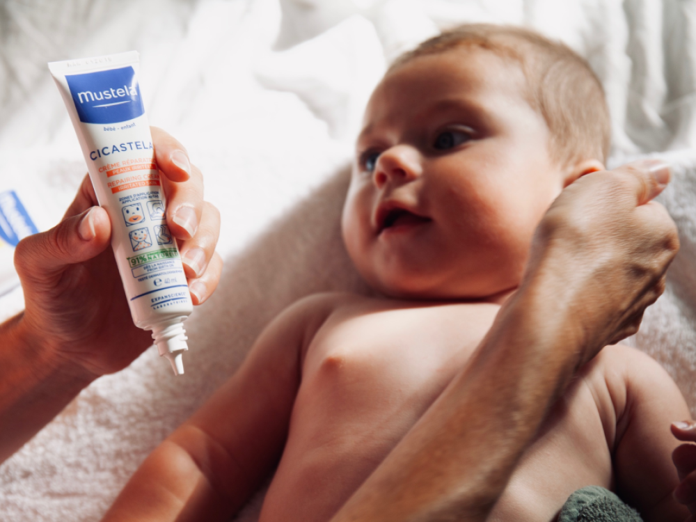 Mustela Cicastela, adult holding the tube beside a baby