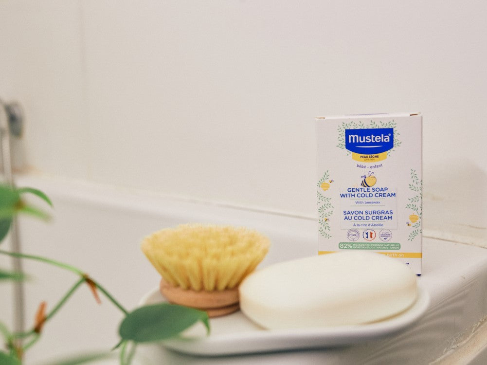 Mustela Cold Cream, box and bar on a soap dish by the bath