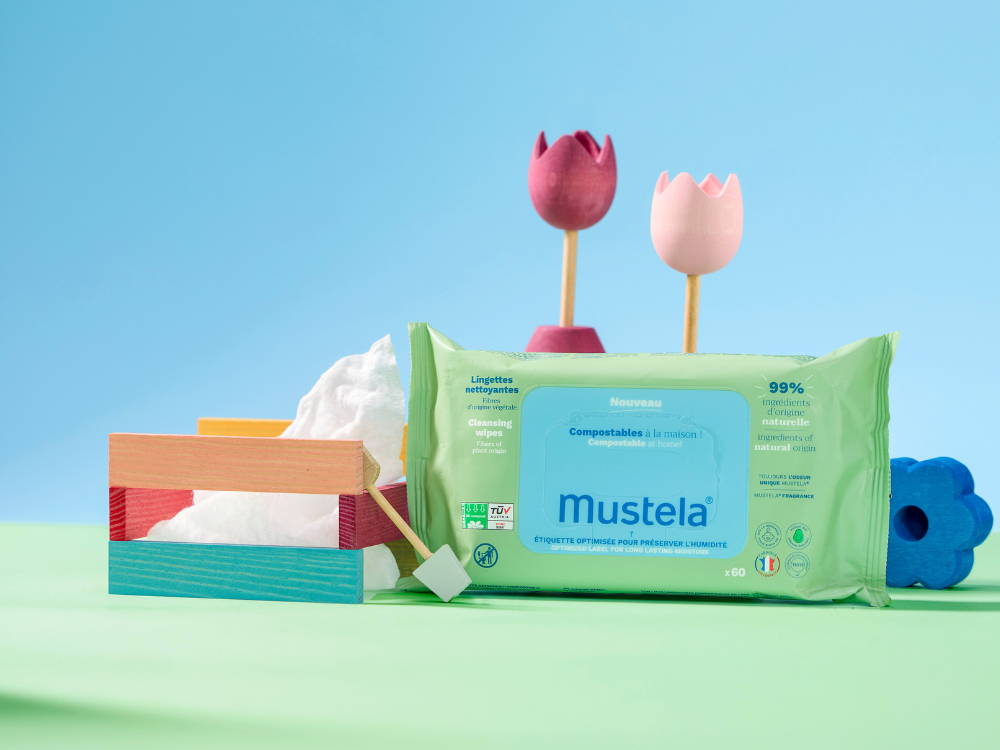 Mustela Compostable Wipes, pack beside wooden toys on a blue and green backdrop