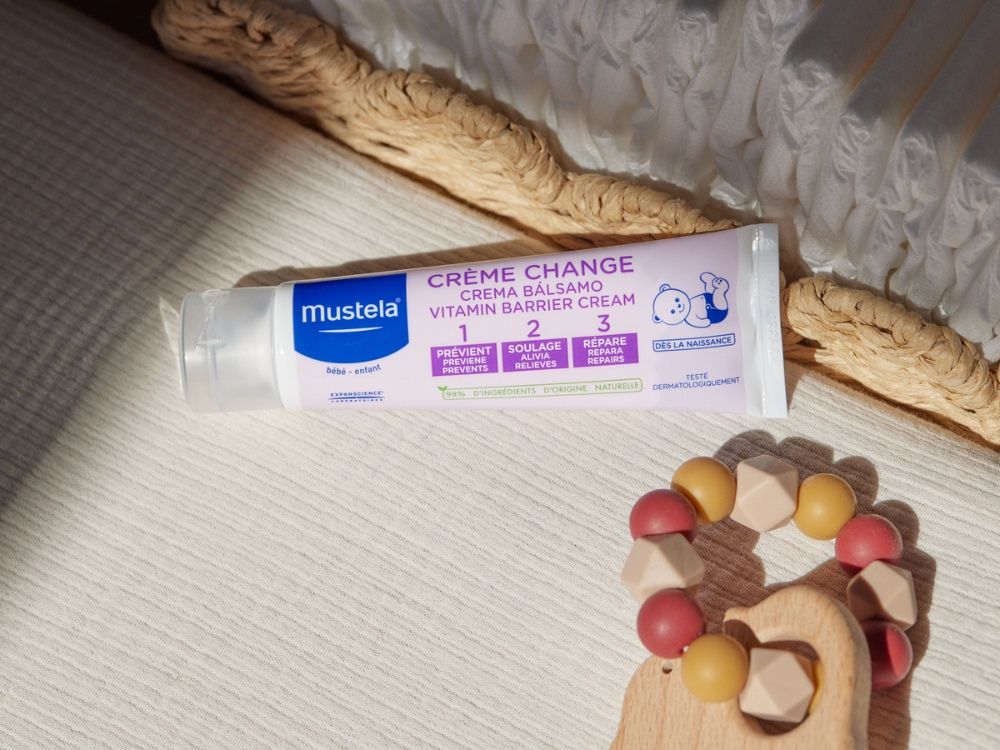 Mustela 123 Diaper Change Cream, tube on a woven blanket beside a wooden baby toy