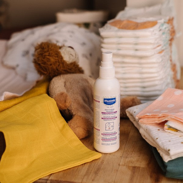 Mustela Diaper Rash Spray, spray bottle with diapers, a plush toy and muslin cloths
