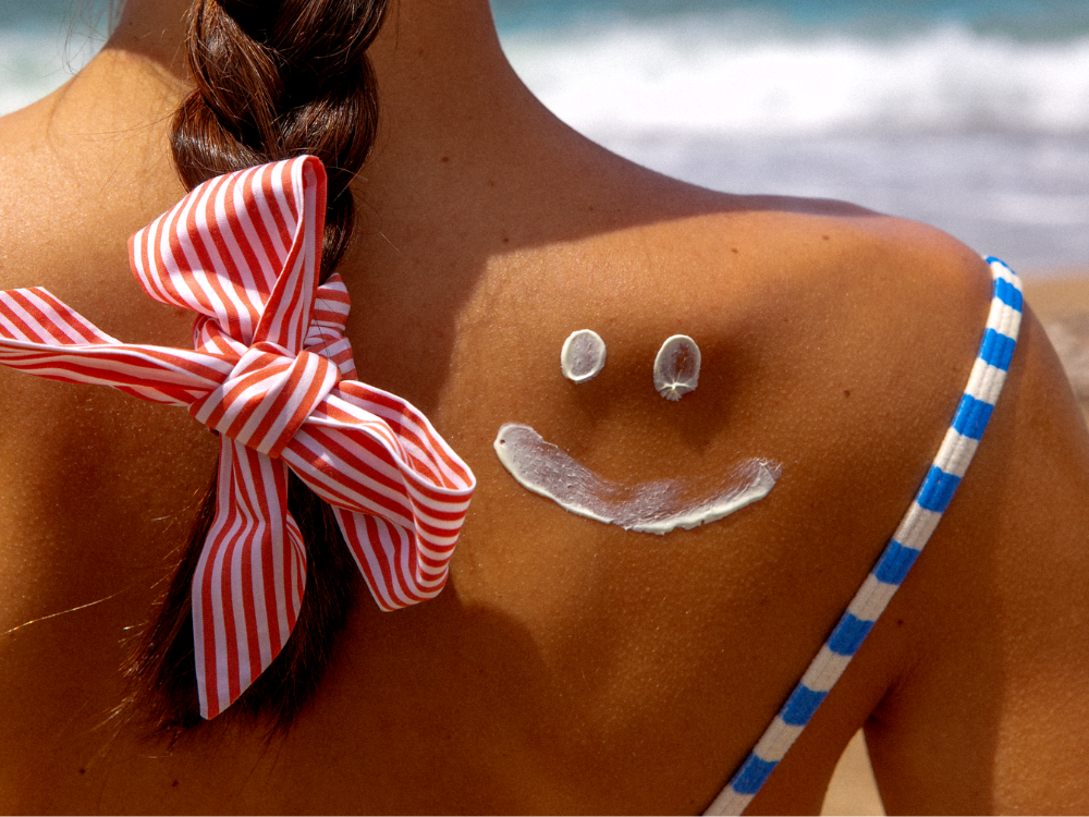 Mustela Sun Spray SPF 50, smiley face drawn in sunscreen on a shoulder