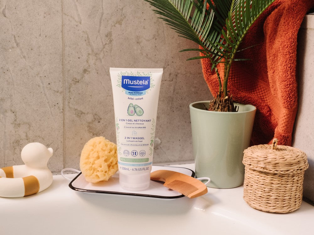 Mustela 2 in 1 Cleansing Gel, tube on a bath tray with a sponge and a toy duck