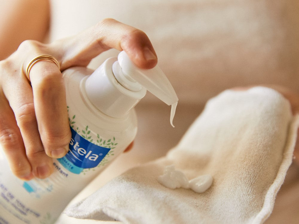 Mustela No-Rinse Cleansing Milk, pump bottle dispensing onto a cotton cloth