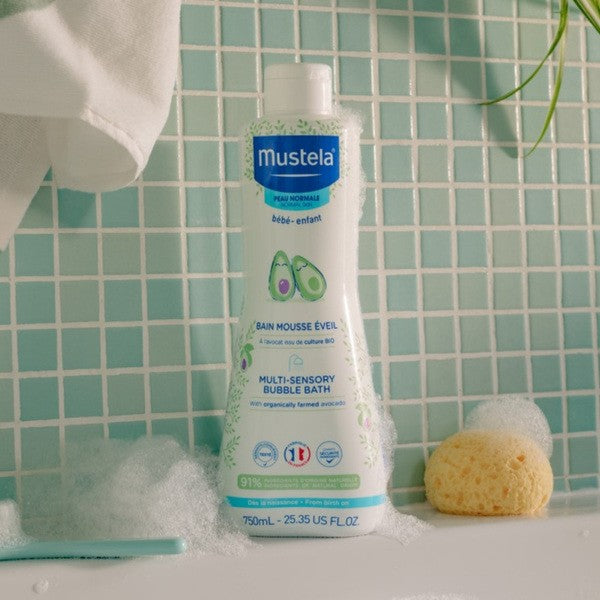 Mustela Foaming Bath, bottle with bath foam and a sponge on tiles