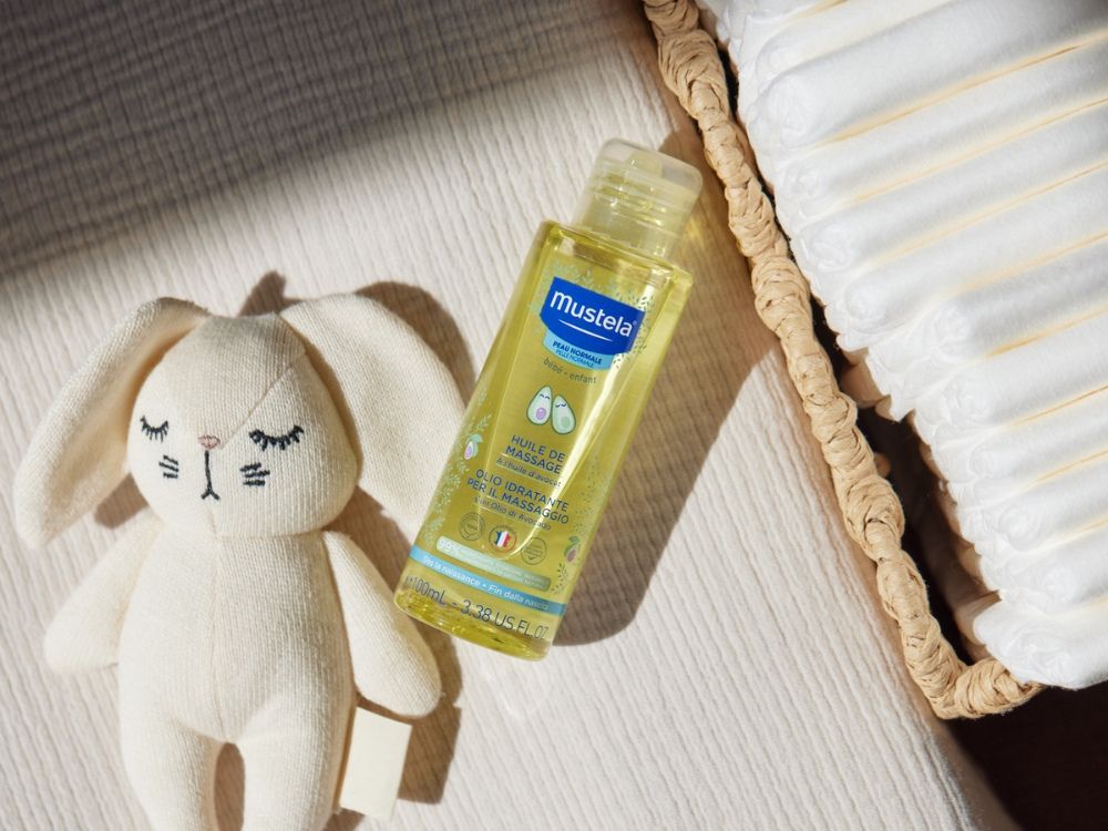 Mustela Massage Oil, bottle beside a plush bunny and a wicker basket