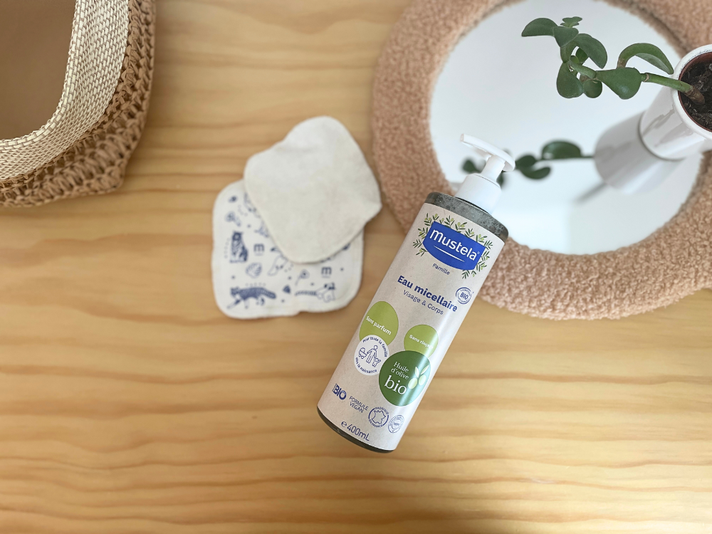 Mustela Organic Micellar Water, pump bottle by a round mirror with reusable cotton pads