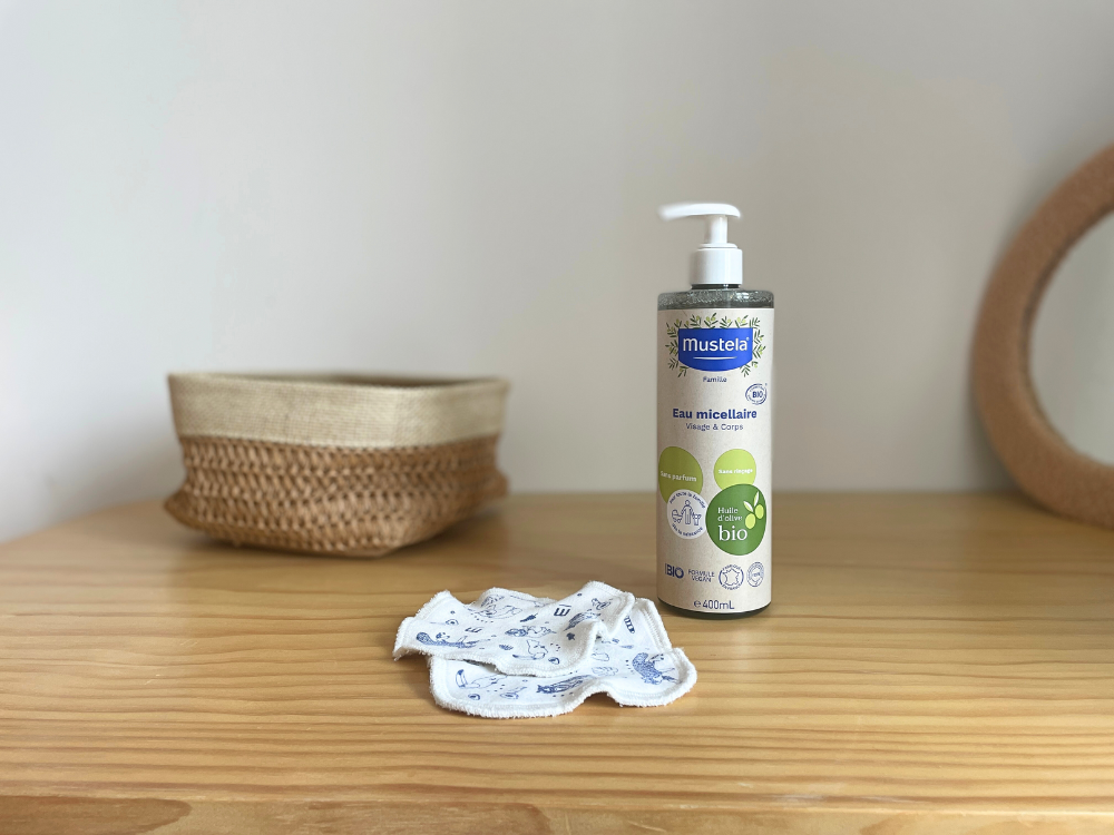 Mustela Organic Micellar Water, pump bottle on a wooden shelf with a basket and pads