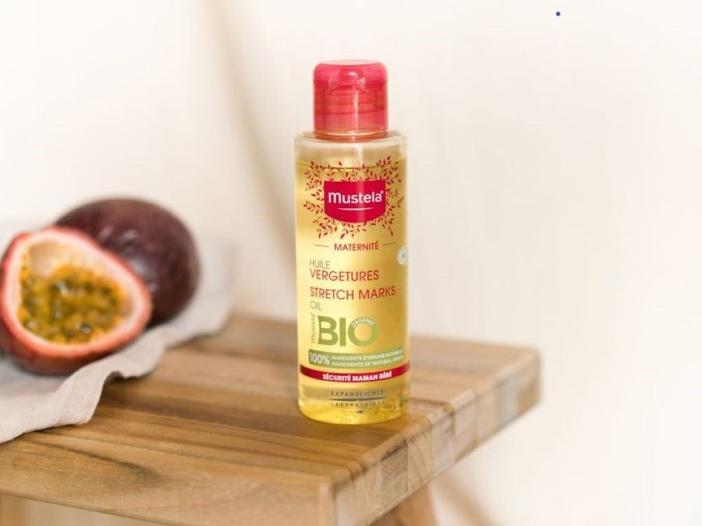 Mustela Maternity, bottle on a wooden stool beside a passion fruit