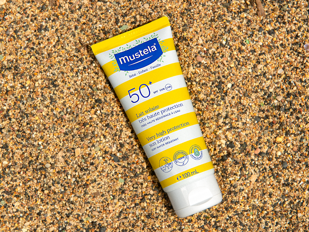 Mustela Lait Solaire, tube lying on the sand