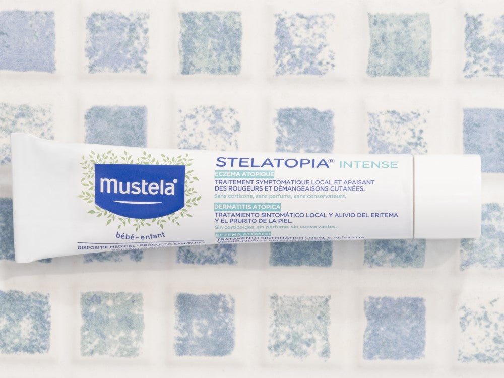 Mustela Stelatopia Intense, tube on a blue and white patterned cloth
